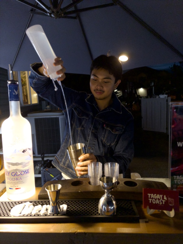Pouring a drink behind the Tagay & Toast bar at night