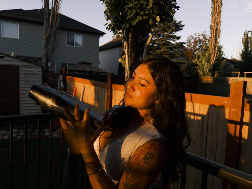 Tianna shaking a cocktail in golden-hour light